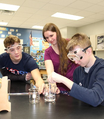 Female science teacher assisting two male students with an experiment Female science teacher assisting two male students with an experiment
